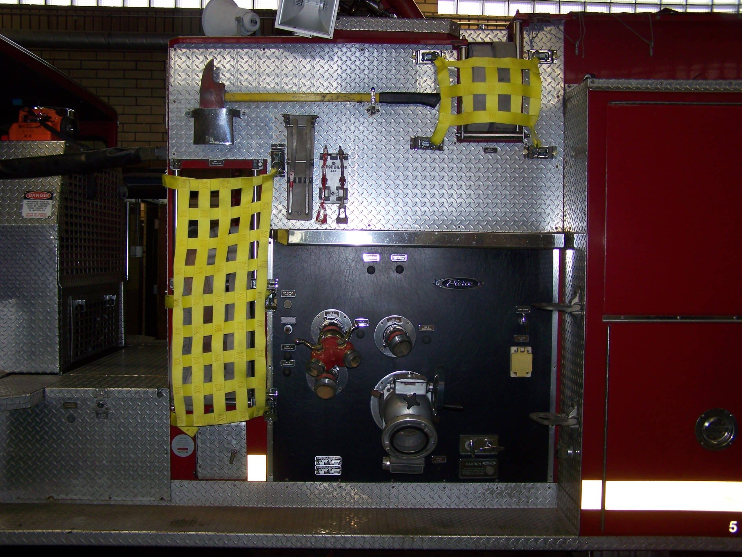 Interior of a fire truck with controls, hoses, and safety equipment.