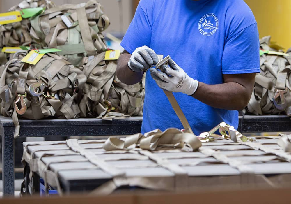 A TAC Industries employee is manufacturing a cargo net.